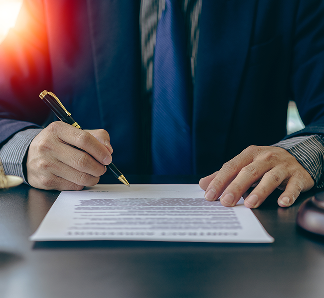 Close-up of an attorney in a suit signing a legal document or settlement agreement, representing professional legal services and successful case resolution.