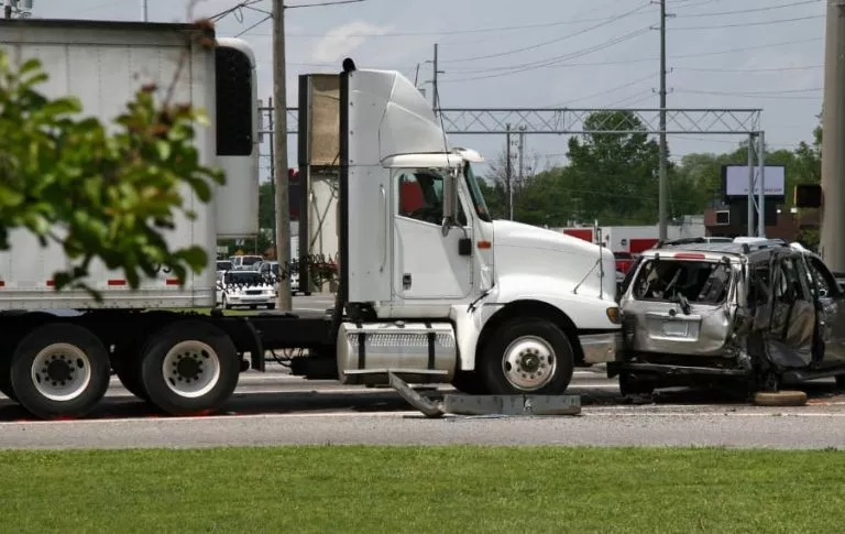 The devastating aftermath of a semi-truck accident where a tractor-trailer has collided with a passenger car.