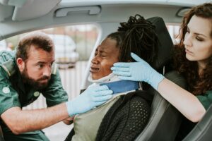 Paramedics placing a cervical collar on a woman who’s suffered car accident injuries.